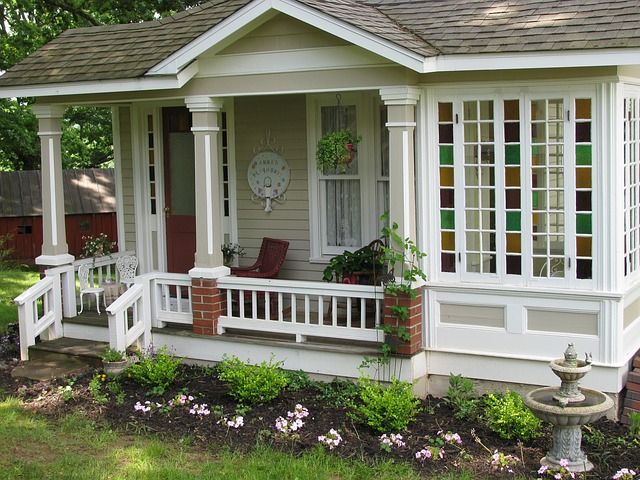 Las mejores ideas de decoración para casas pequeñas, a nice house with dark gray roof tiles, light gray paneling, white columns, and white window and door trim.